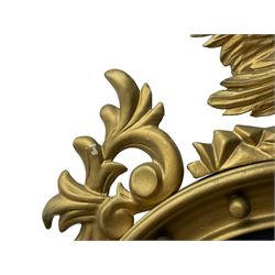 Pair of Regency period giltwood convex wall mirrors, moulded circular frame decorated with spherical mounts surmounted by a carved eagle with spread wings, foliage scroll carved upper and lower brackets, reed moulded and ebonised slip enclosed convex mirror plate 