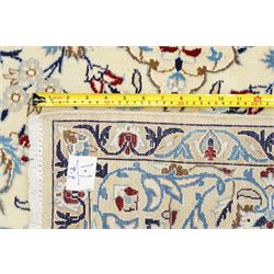 Central Persian Nain hand-knotted rug, ivory field with central medallion in tones of indigo and blue, issuing vinery, palmettes and floral sprays with conforming spandrels, dark blue main border of floral vinery and stylized palmettes, framed by multiple guard borders, with cotton fringe ends 