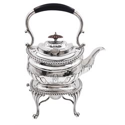 Edwardian silver spirit kettle on stand, the teapot of oval part fluted form with wooden finial, part ebonised carry handle and engraved motif to centre, upon a silver stand of oval form upon four curved and stylised pad feet, with removable silver burner, hallmarked Elkington & Co Ltd, Birmingham 1902, approximate gross weight 42.21 ozt (1313.1 grams)