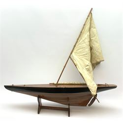 Pond yacht with part black painted mahogany hull and keel, working rudder and mast with three sails W90cm H95cm, loose mounted on mahogany stand