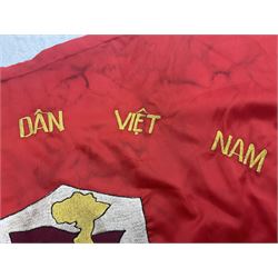 1960s North Vietnam banner embroidered in yellow thread on a red ground, roughly translates as 'Peoples Army of Viet Nam. Warriors of Viet Nam Determined To Keep The Country 1964' around a central military crest with the motto 'Warriors Keep The Country'; tassels to three sides 70 x 100cm