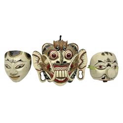 Three carved wooden Balinese topeng masks, one depicting Rangda and two others 