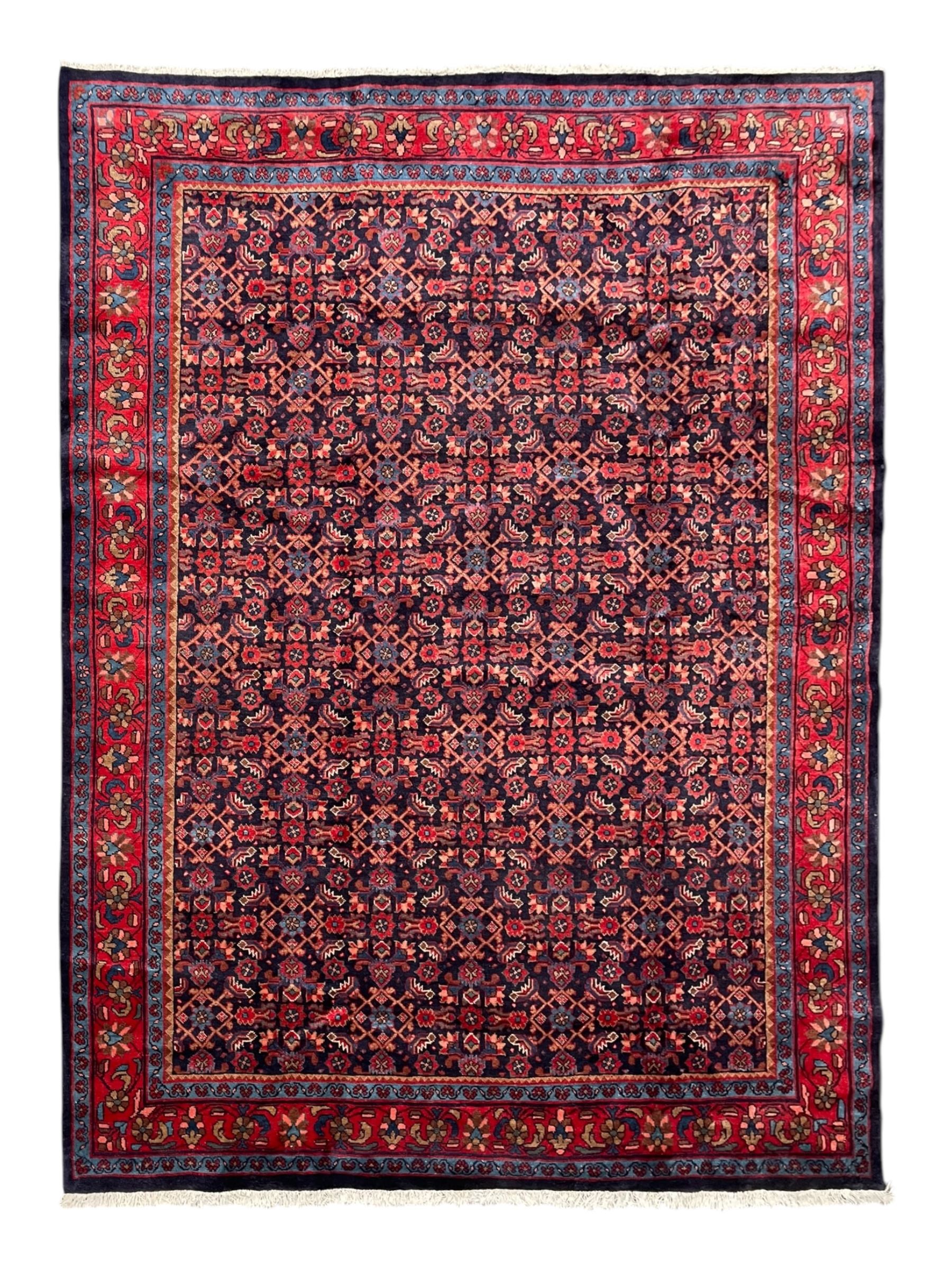 Persian indigo ground rug, the field decorated all over with floral Heratti motifs, crimson border with trailing stylised flower heads, within guard stripes