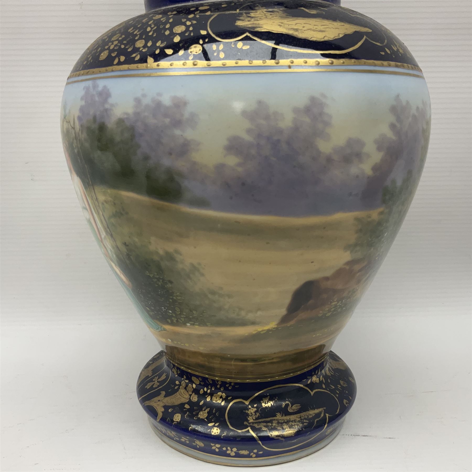 19th century Vienna style porcelain 'Musik' garniture, the central vase of baluster form with domed cover flanked by two smaller vases with twin curved gilt handles to short neck, each decorated with classical figural vignettes between blue borders heightened with gilt, H33.5cm