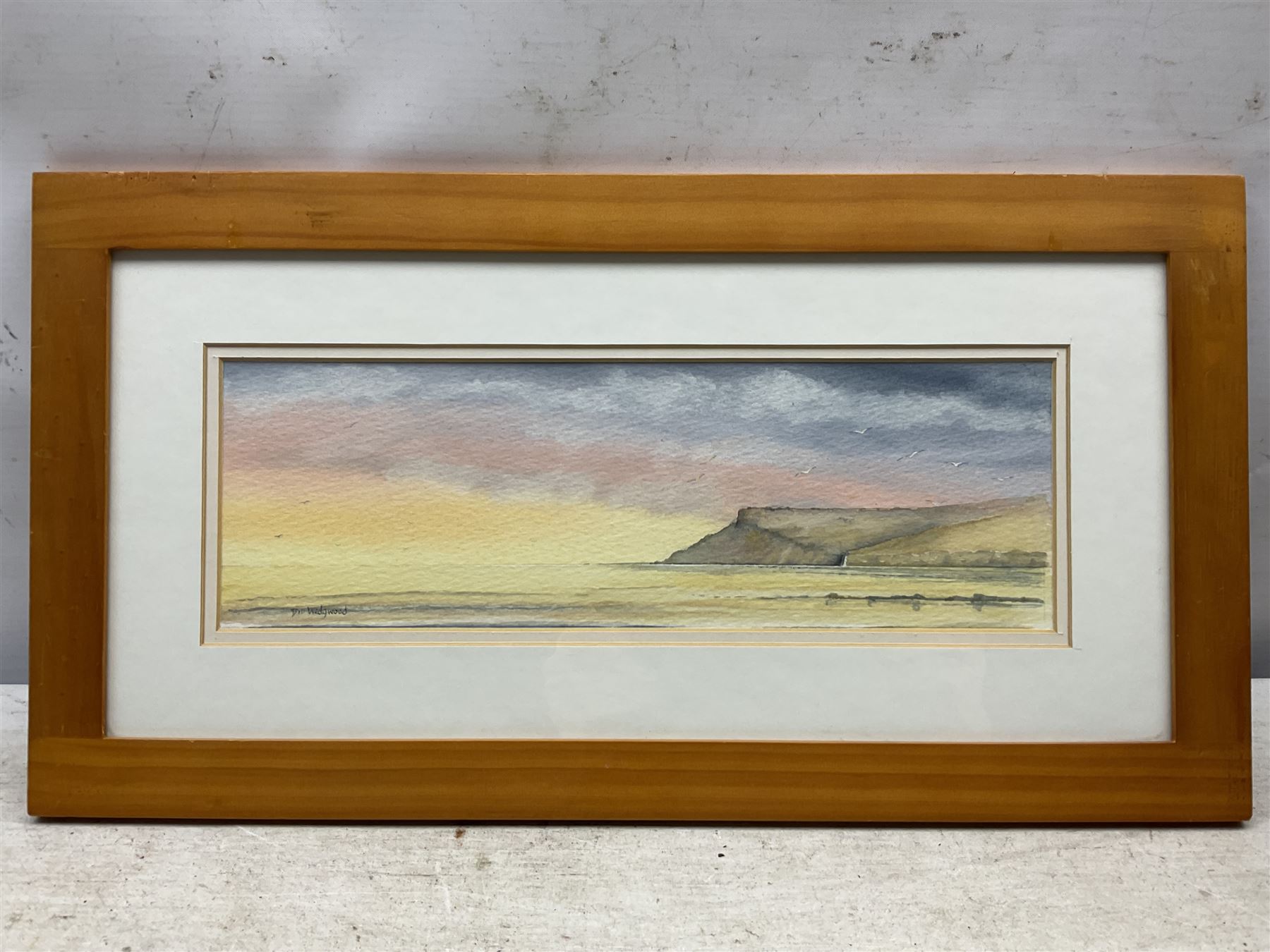 W Keeland (British 20th Century): Coastal Town, oil on board signed 15cm x 47cm; William 'Bill' Wedgwood (British c1934-2019): Ravenscar from Robin Hoods Bay, watercolour signed, max 15cm x 47cm (2)