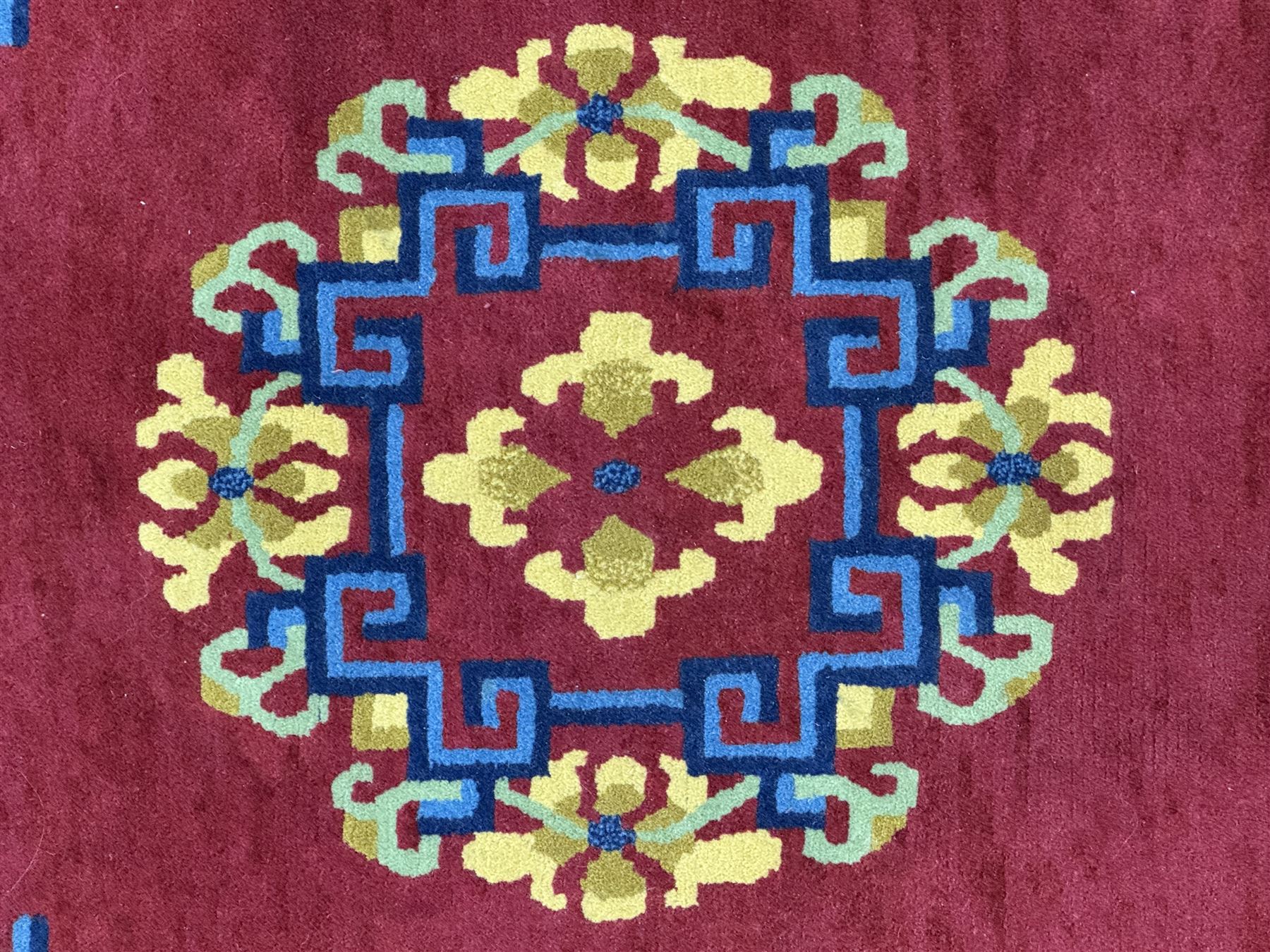 Tibetan-design handwoven rug, deep red field with three central medallions in yellow and blue, traditional yellow key border, white fringes on both ends