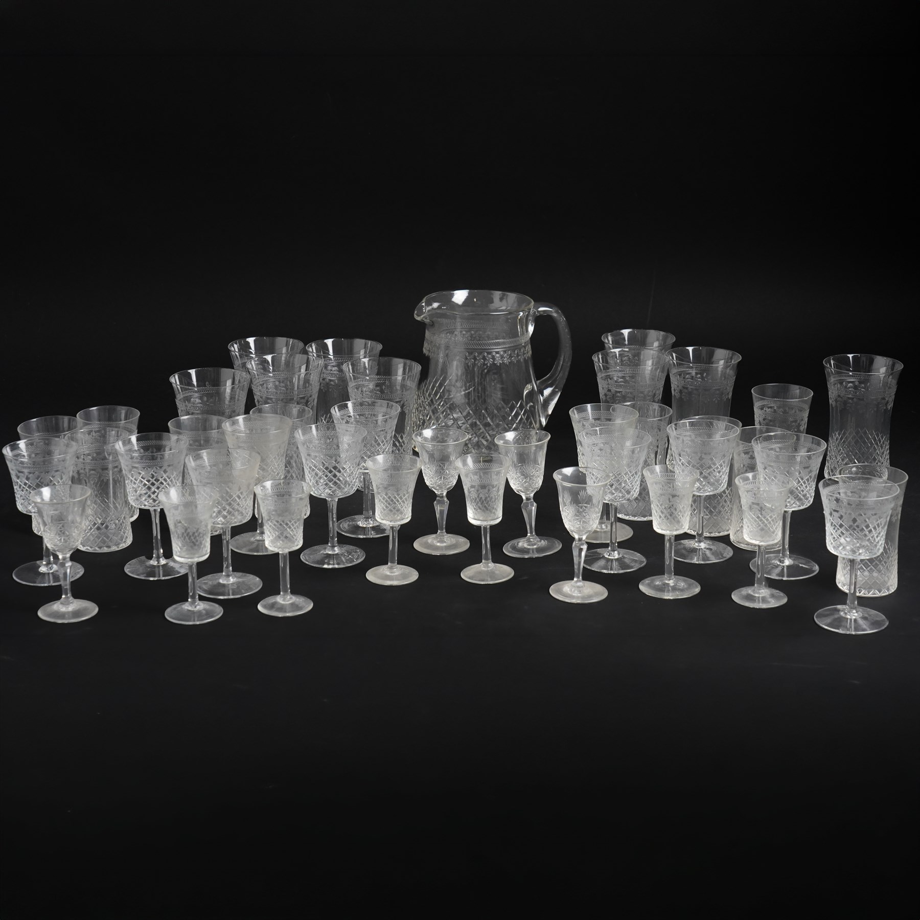Suite of early 20th century cut and etched table glass comprising nine tumblers, ten smaller tumblers, eleven small wine glasses, six sherry glasses and water jug together with four other sherry glasses
