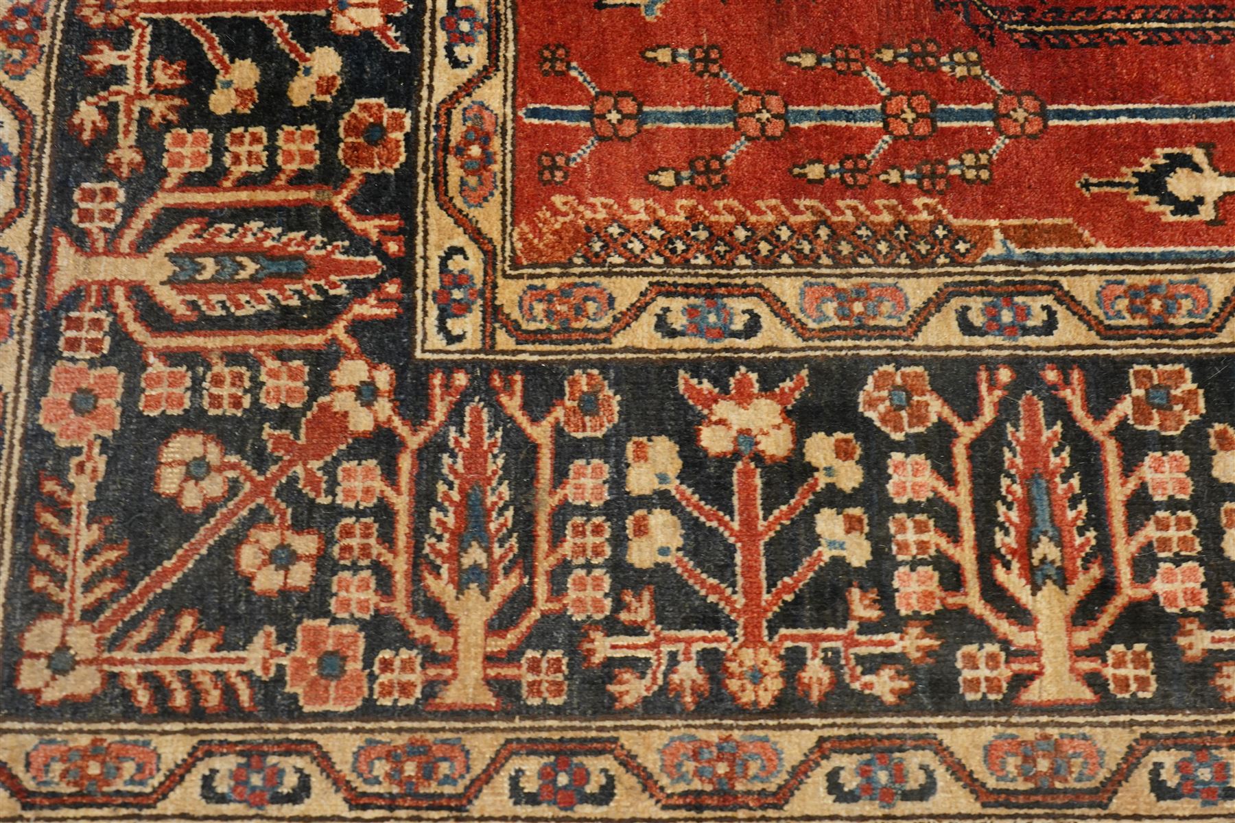 Anatolian crimson ground tribal rug, the field decorated with repeating geometric tree of life motifs with figural designs, the indigo guard band with stylised palmettes