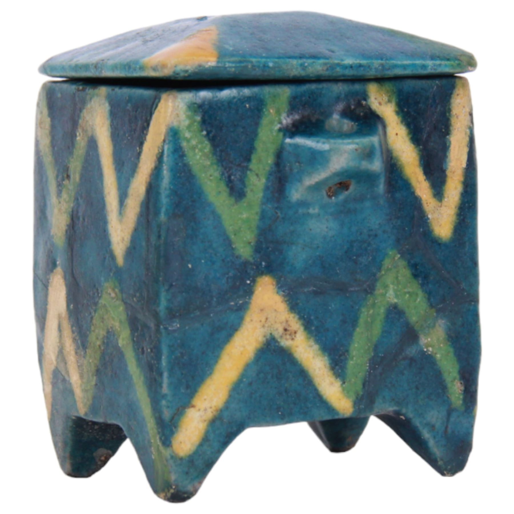 Raqqa ware pottery model of a monkey, probably Assyrian, modelled in crouching position, with turquoise and blue glaze, H6cm, together with a Raqqa ware pottery pot, also probably Assyrian, of square sided form, twin lug handles and canted cover, upon four tapering feet, decorated with yellow and green zig-zag bands upon a turquoise glazed ground, H8cm