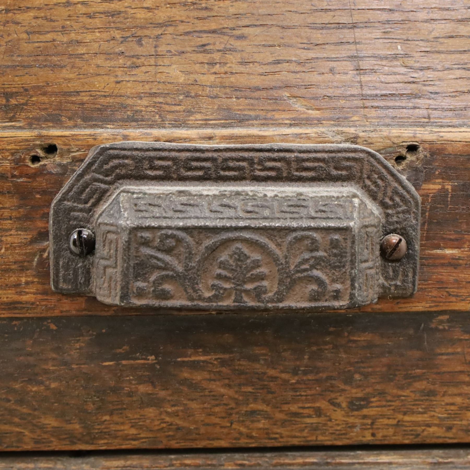 18th century rustic oak dresser base, with fielded panels and iron cup handles with embossed greek key and foliate detail, three short drawers above and open recess flanked by two cupboard doors, raised on stile supports