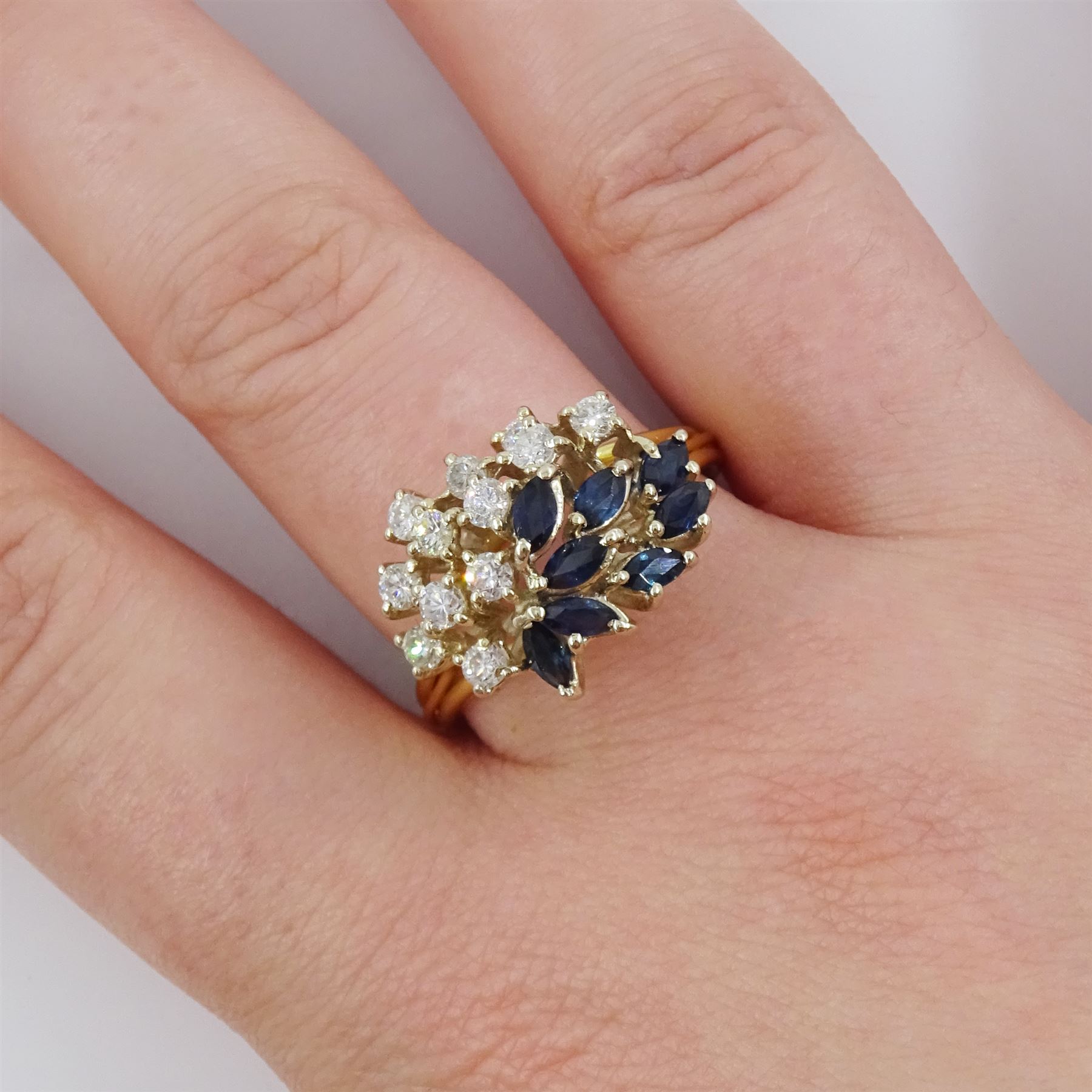 18ct gold sapphire and diamond cluster ring, twelve round brilliant cut diamonds and eight marquise cut sapphires, in a swirl design setting, Sheffield import mark 1989, total diamond weight approx 0.70 carat