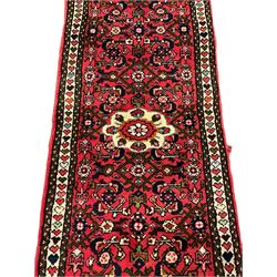 Persian red ground runner, decorated with large Herati motifs and shaped central medallion, the guarded border decorated with repeating heart motifs
