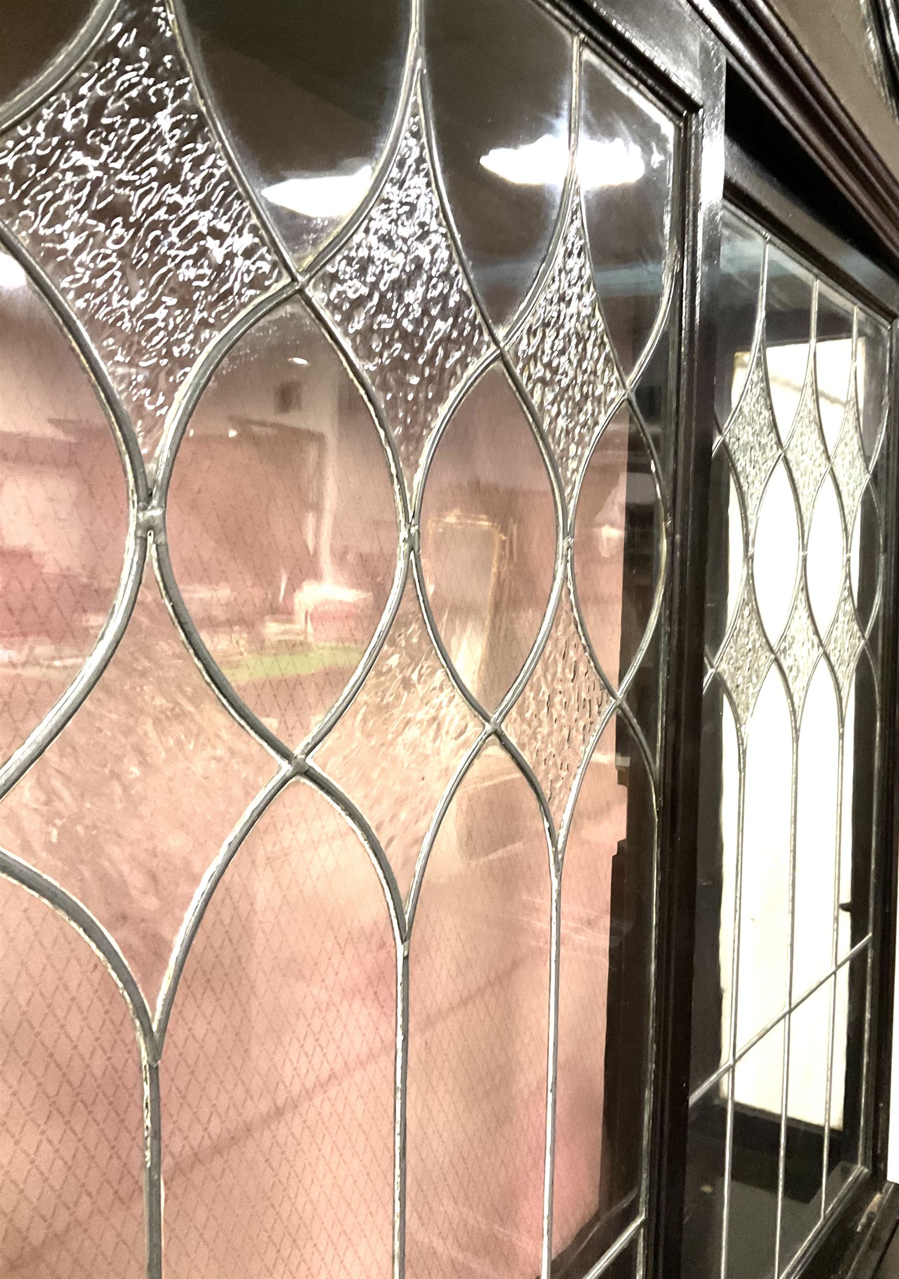 Late 19th century mahogany Empire style display cabinet, swan neck pediment and carved urn finial over two lead glazed doors enclosing two shelves, two glazed doors under, raised on cabriole front supports