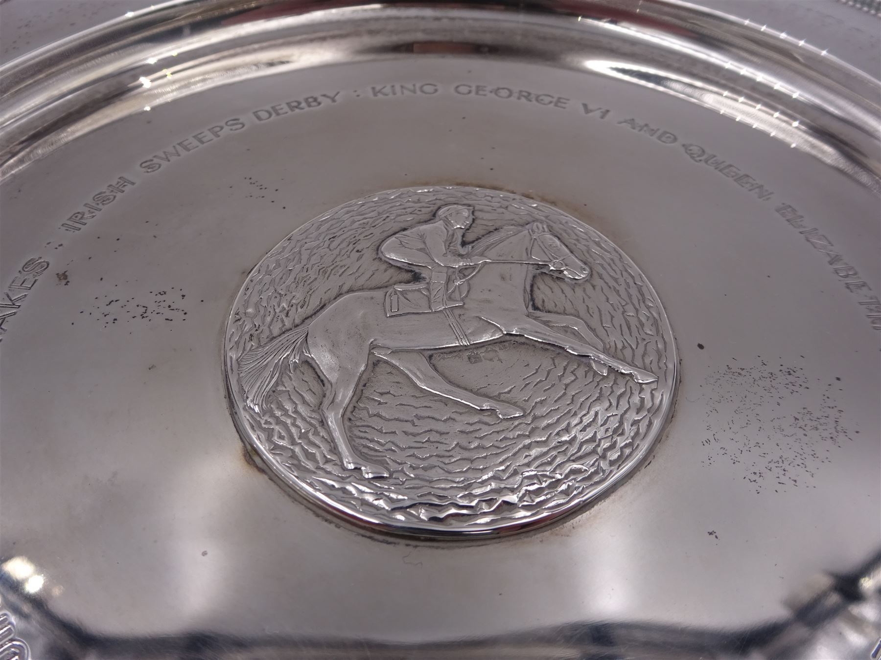 Modern limited edition silver salver, celebrating the achievements of Grundy, champion racehorse of 1975, each of circular form with gadrooned rim and plaque to centre depicting jockey mounted upon Grundy, designed by Stuart Devlin, limited edition no. 15/500, hallmarked London 1976, makers mark LH, D23cm, within silver lined fitted box and limited edition certificate 