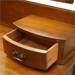 Manner of Liberty & Co. - Arts & Crafts oak dressing chest, the arched swing mirror with roundel-carved frieze and bevelled plate, serpentine-front top with two raised trinket drawers, fitted with two drawers with brass Art-Nouveau poppy handle-plates, on square tapering supports with castors