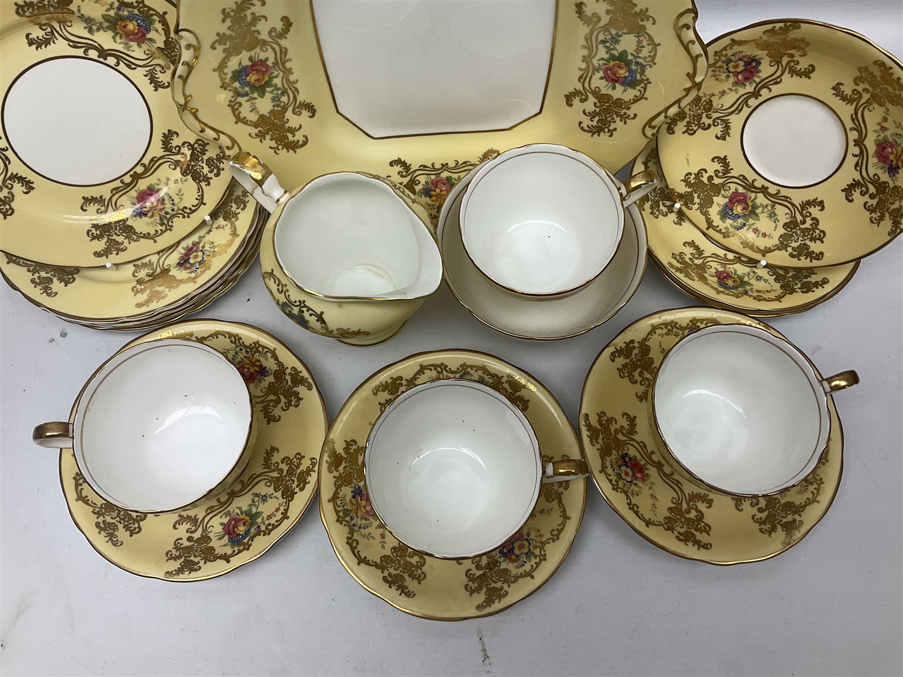 Aynsley tea service for six, decorated with floral sprays in ornate gilt detailing on cream ground, comprising six teacups and saucers, open sucrier and milk jug and cake plate, all with printed marks beneath