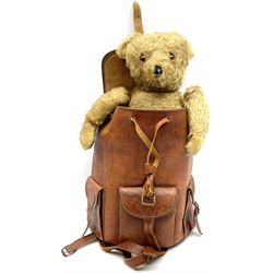Mid-20th century plush covered teddy bear the revolving head with applied eyes, vertically stitched nose and jointed limbs with rexine pads H58cm; together with a leather backpack (2)