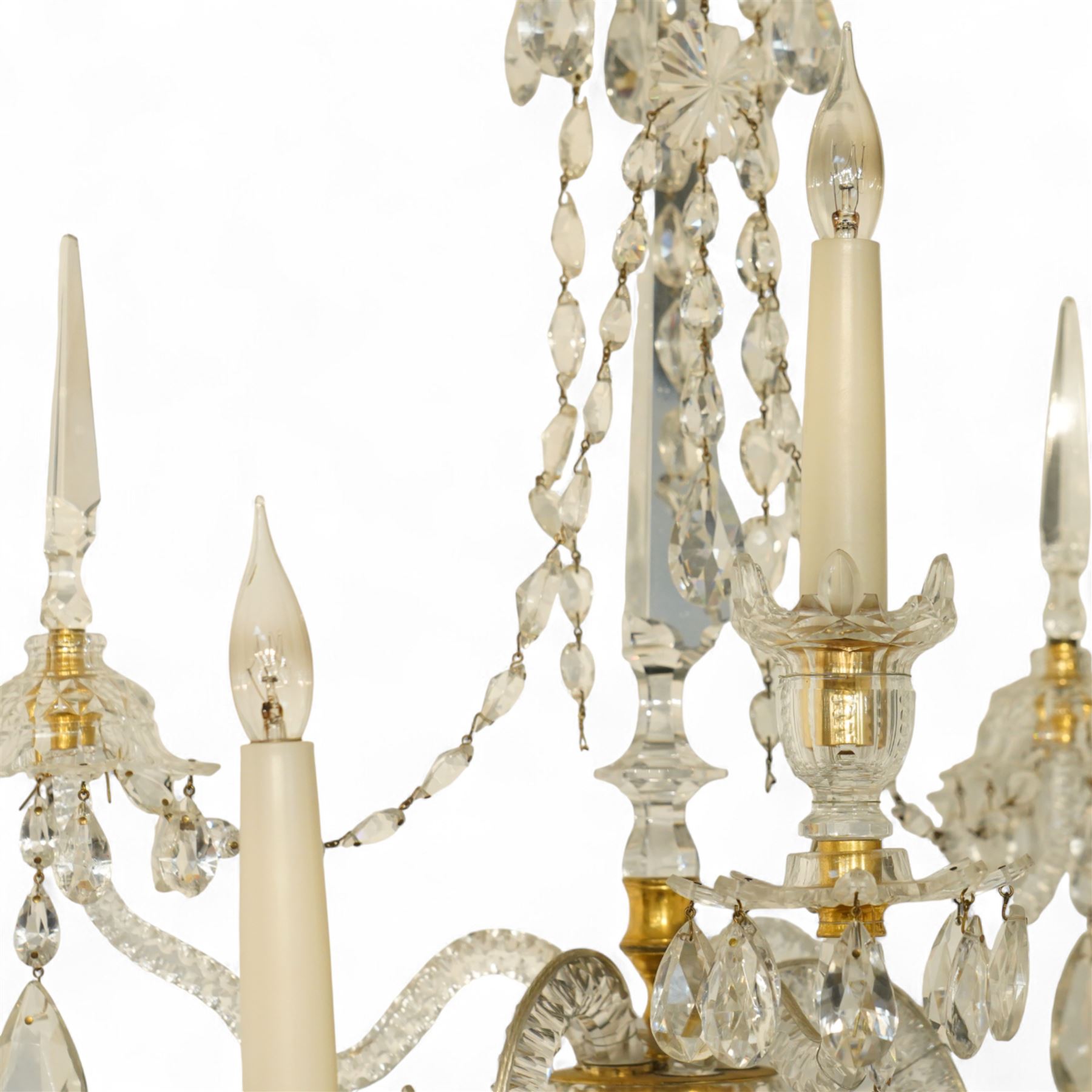 Pair of George III ormolu and cut-glass wall-lights, each with a tall central urn-shaped finial above a series of faceted glass spires and scrolled branches, the ormolu-mounted nozzles and drip pans hung with festoons of cut-glass drops and pear-shaped pendants, the lower section centred by a pineapple finial, wired for electricity