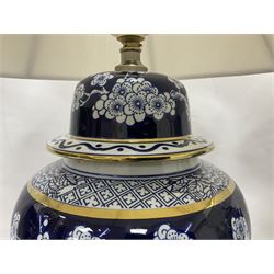 Pair of blue and white table lamps, each of baluster form, decorated with prunus blossom, within stylised borders, raised upon circular gilt base, excluding fittings H48cm