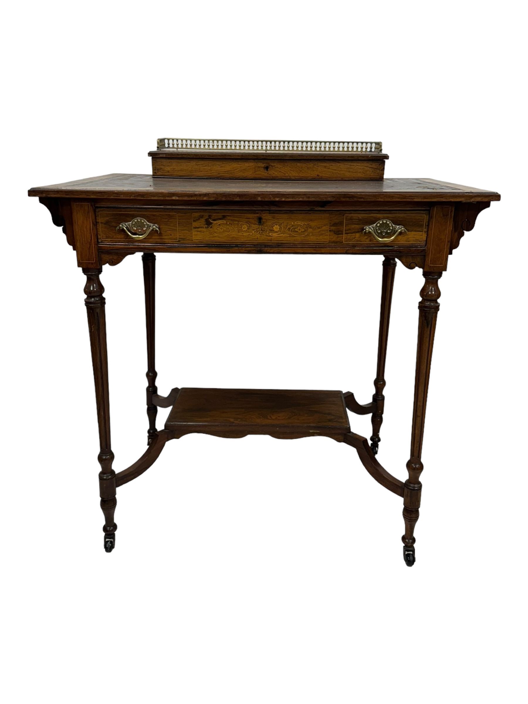 Late Victorian walnut writing table, rectangular leather-inset top surmounted by a brass gallery, fitted with a single frieze drawer, raised on turned tapering supports with lower undertier and ceramic castors