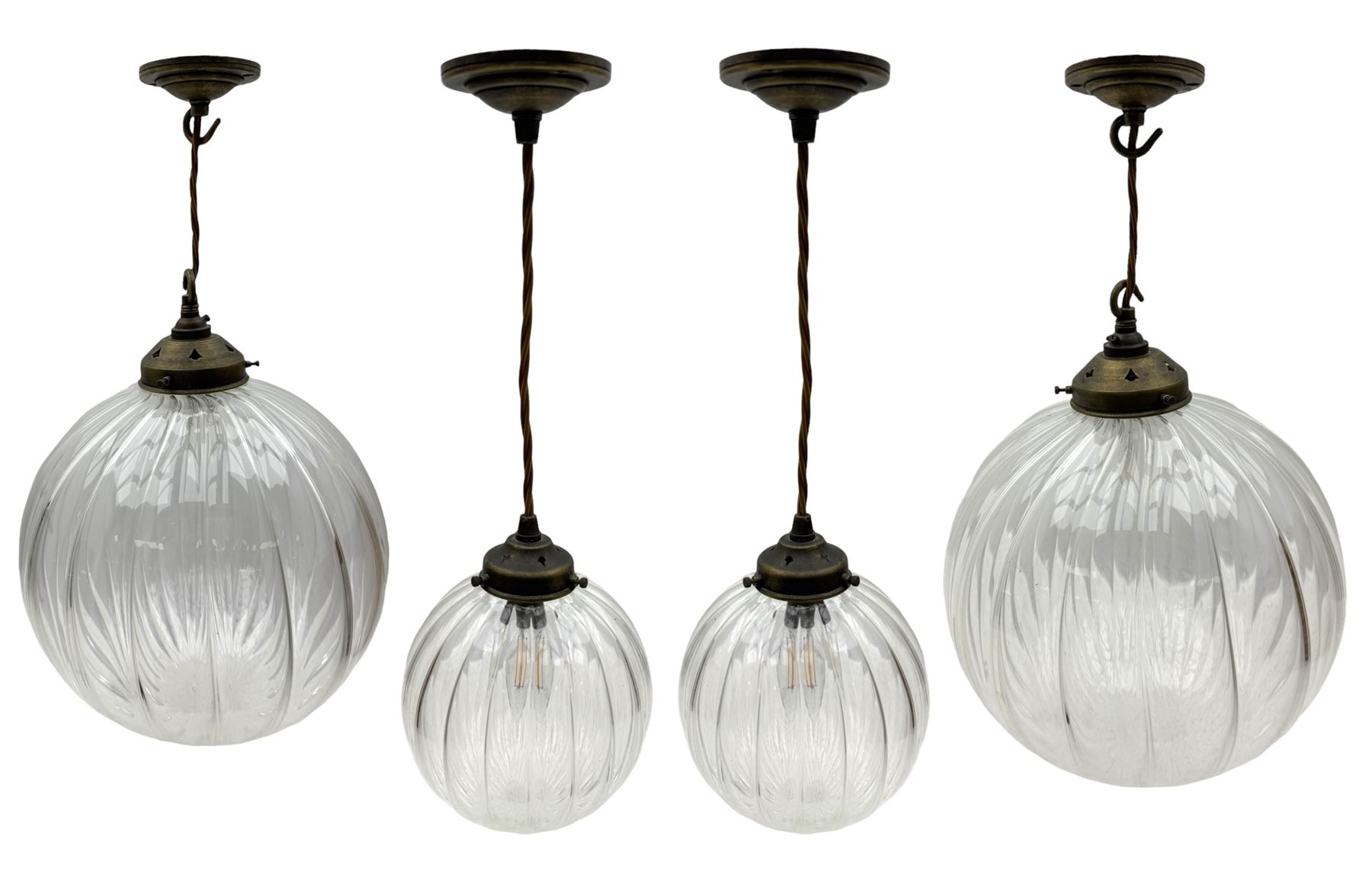 Set of two small and two large pendant lights, each with clear glass spherical shade with moulded swirl pattern, suspended from twisted cords, brass ceiling rose