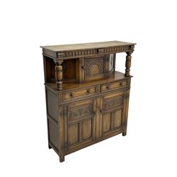 Jacobean design oak court cupboard, upper section with carved arched panelled cupboard door flanked by turned columns, beneath carved and moulded frieze, lower section fitted with two drawers over two cupboard doors with gothic arched panel decoration, raised on stile supports