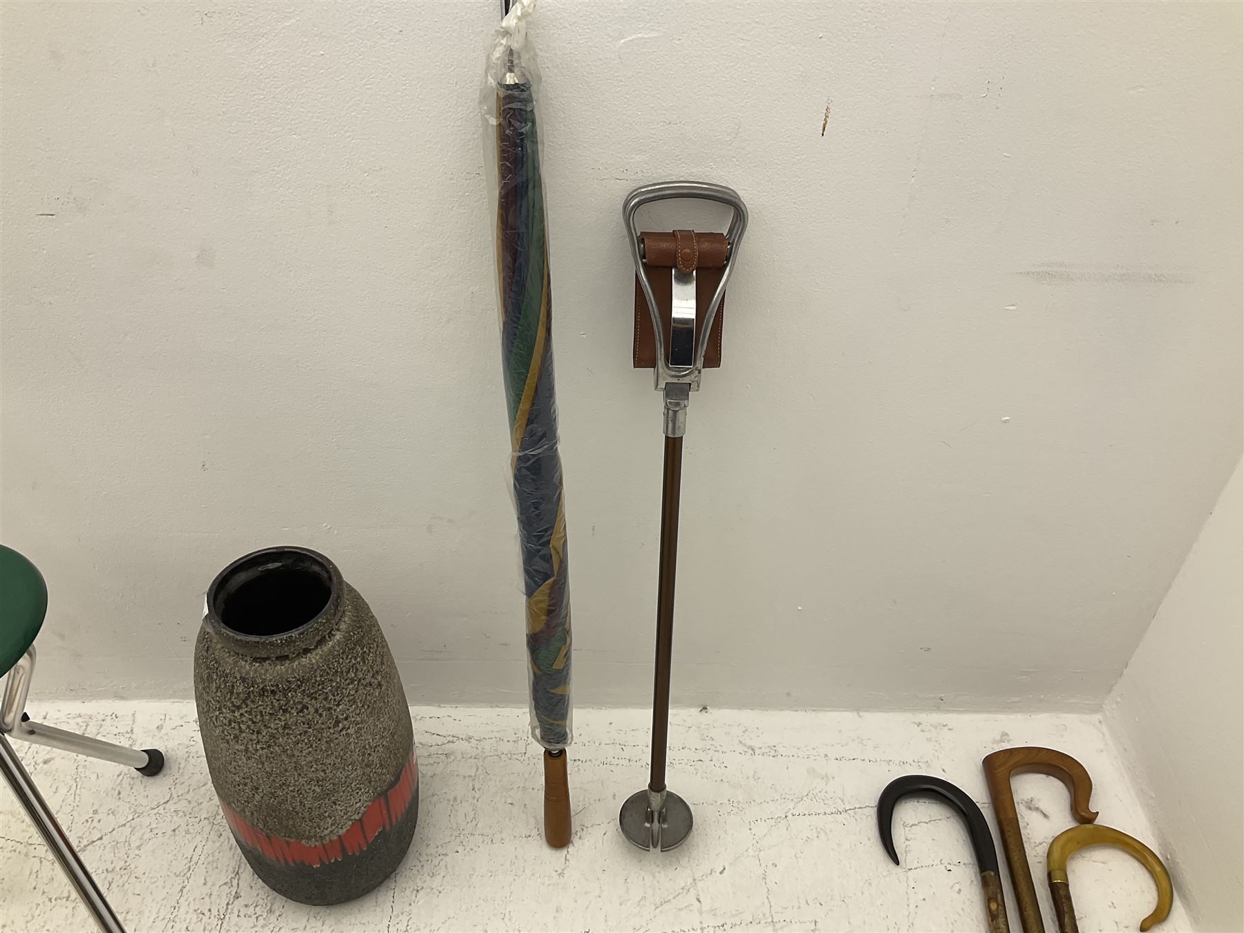 Two smooth polished ram horn handled Shepherd's crooks and a further similar example, together with various shooting sticks, walking sticks and canes, housed in a volcanic lava glaze West German style vase