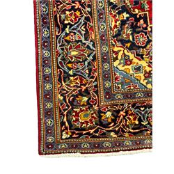 Central Persian Kashan crimson ground rug, central indigo pole medallion surrounded by sparsely placed bouquets interconnected with foliate branches, the guarded border with repeating palmette and Boteh motifs with interwoven scrolling patterns, framed by guard stripes