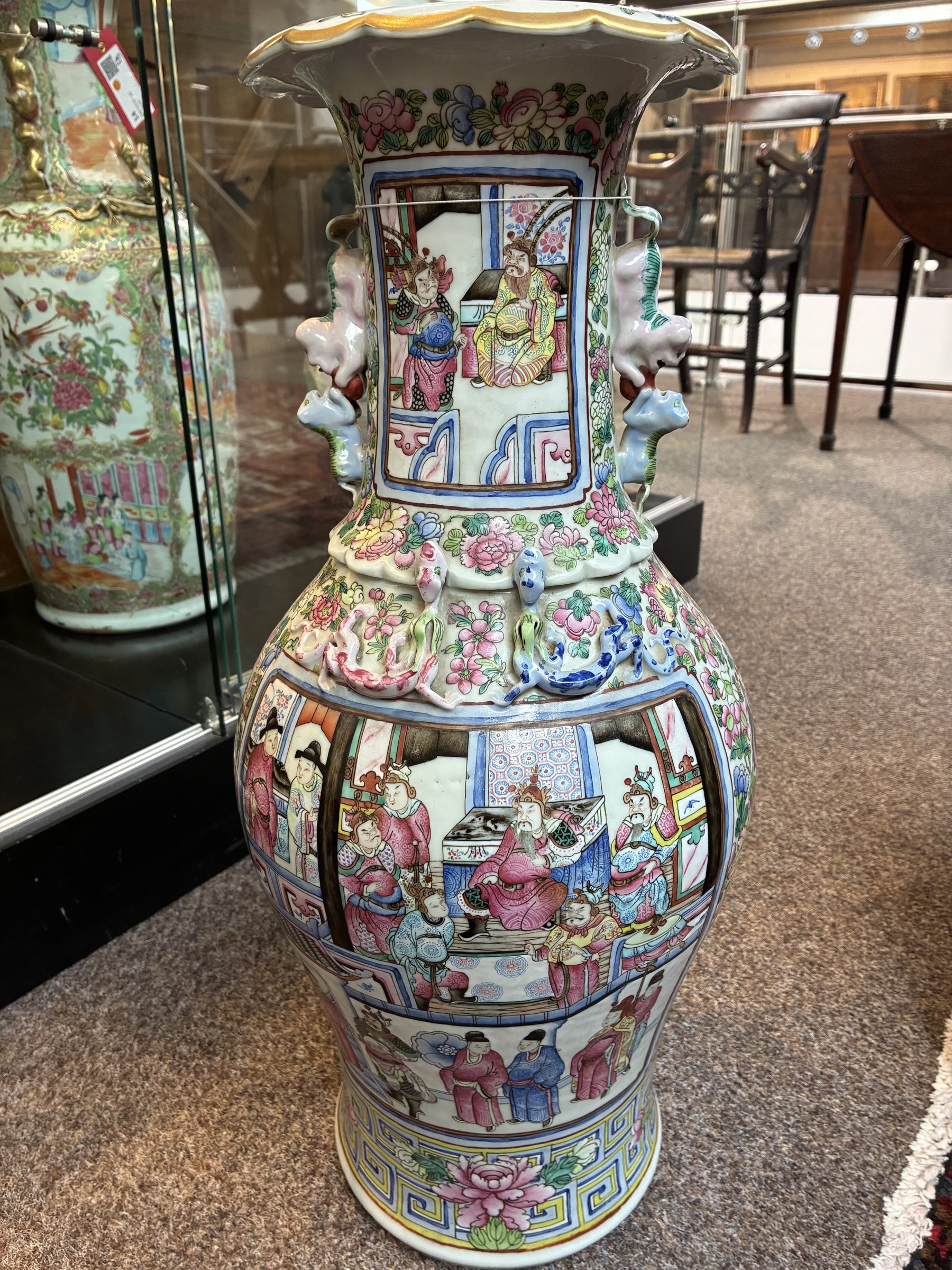 Large pair of 19th century Cantonese famille rose vases, each painted with various courtly scenes, including a display of warriors fighting on horseback before an official and his attendants, double Buddhist lion handles and applied at the shoulders with chilong, the lower band painted with Greek key motif, H58cm (2)