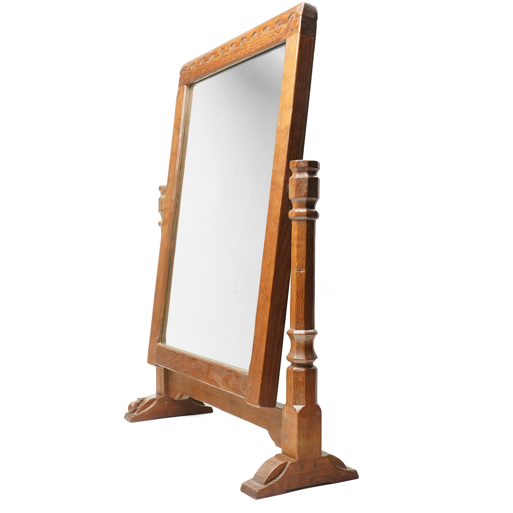 Mouseman - 1930s/40s lightly adzed dark oak dressing table swing mirror, the arcade carved cresting rail over a rectangular plate, the mirror pivots between two lappet-carved turned octagonal supports with dished tops, raised on sledge feet, with carved mouse signature, by the workshop of Robert Thompson of Kilburn