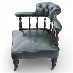 19th century green leather upholstered corner chair, with deep buttoned back and swept padded arms with close studded borders, raised on turned supports united by turned spindles, terminating in brass castors