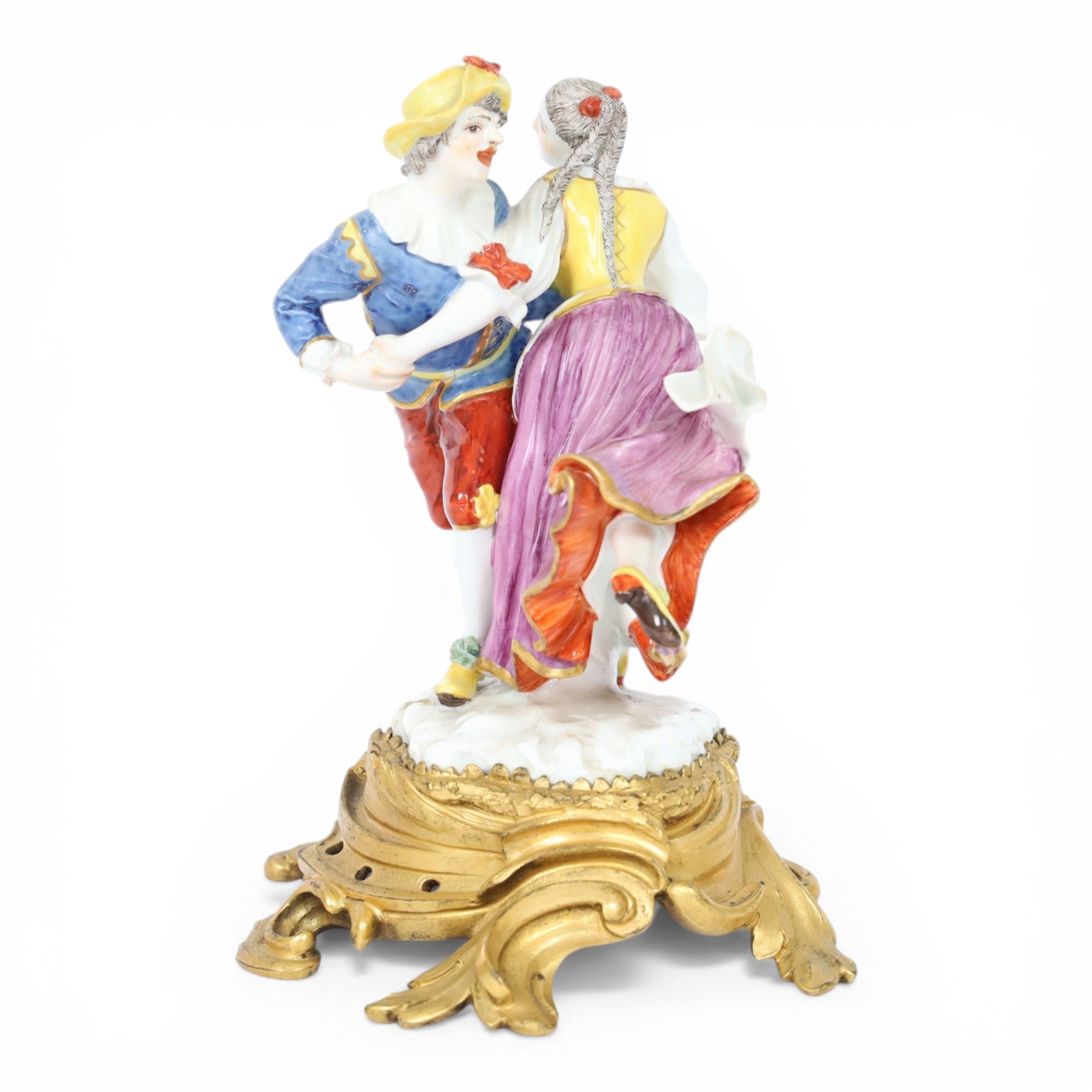 Mid 18th century Meissen figure group, The Tyrolean Dancers, circa 1740, modelled as two swirling figures with their arms linked, he in yellow hat with red rosette, blue jacket, red breeches with red rosette, and yellow shoes with green rosette, she in white blouse with red ribbons, yellow and red bodice, white apron over puce skirt and yellow shoes with green rosettes, her hair fashioned into two plaits secured by red ribbon, upon a shaped mound base, within a scrolling gilt metal mount, with blue crossed swords mark to base, overall H19cm
