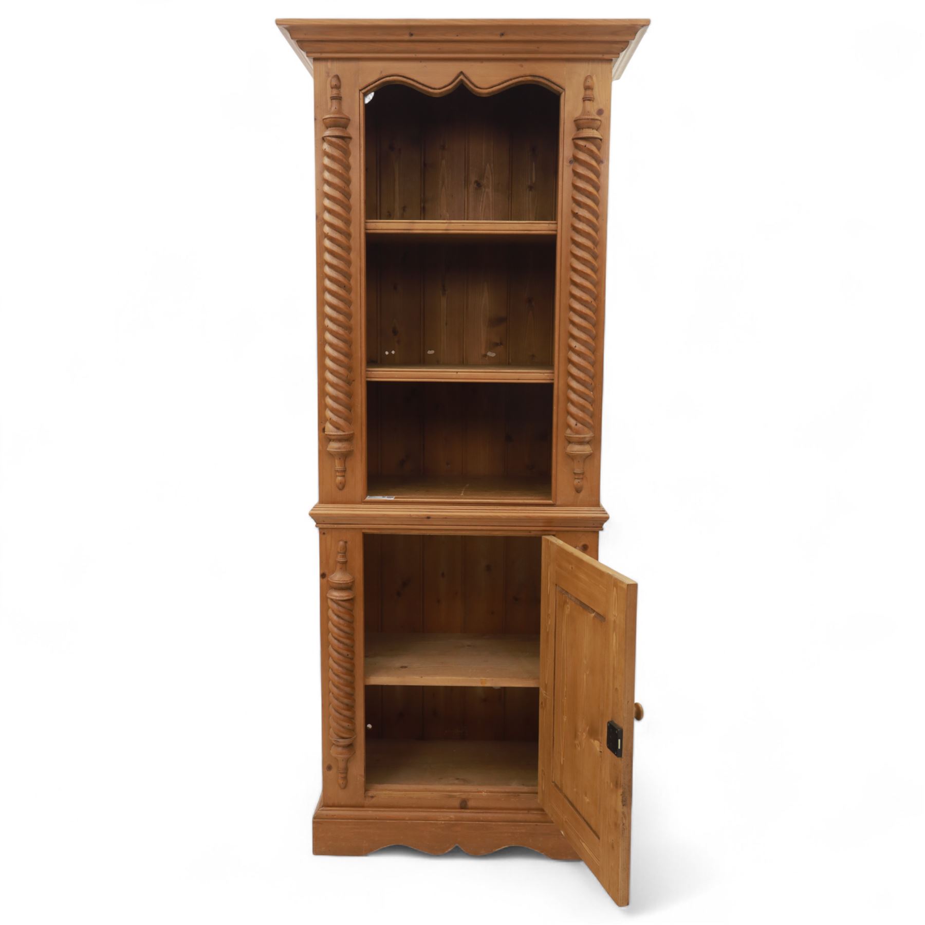 Contemporary stripped pine bookcase cabinet, the upper section with arched frieze and open shelving flanked by barley twist columns, over a single door cupboard base with matching twist supports and fielded panel door