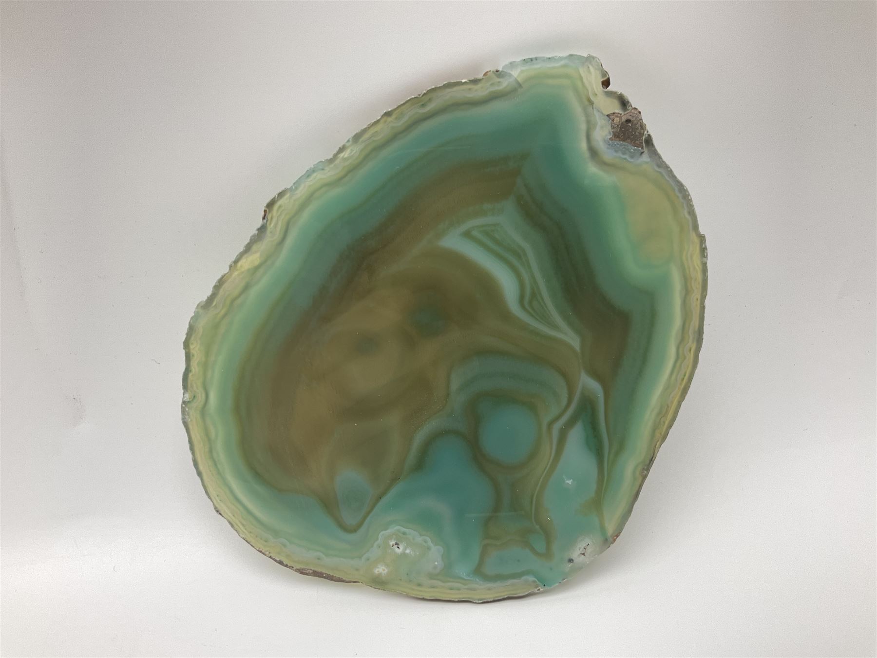 Pair of green agate slices, polished with rough edges, raised upon silvered metal stands, H23cm