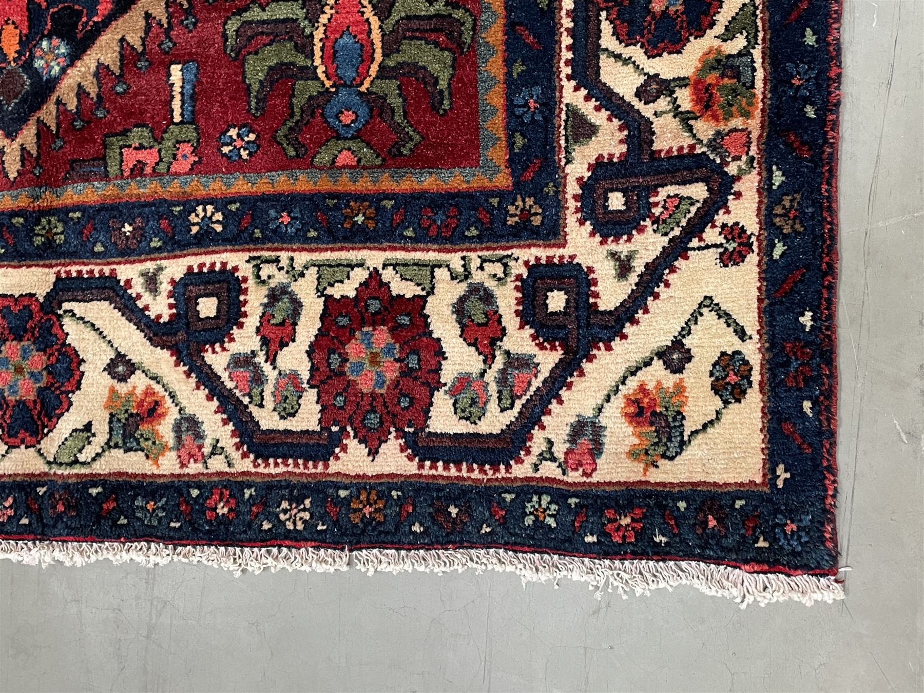 Persian Hamadan rug, the red ground field decorated with two floral medallions and stylised flower heads, repeating guarded border