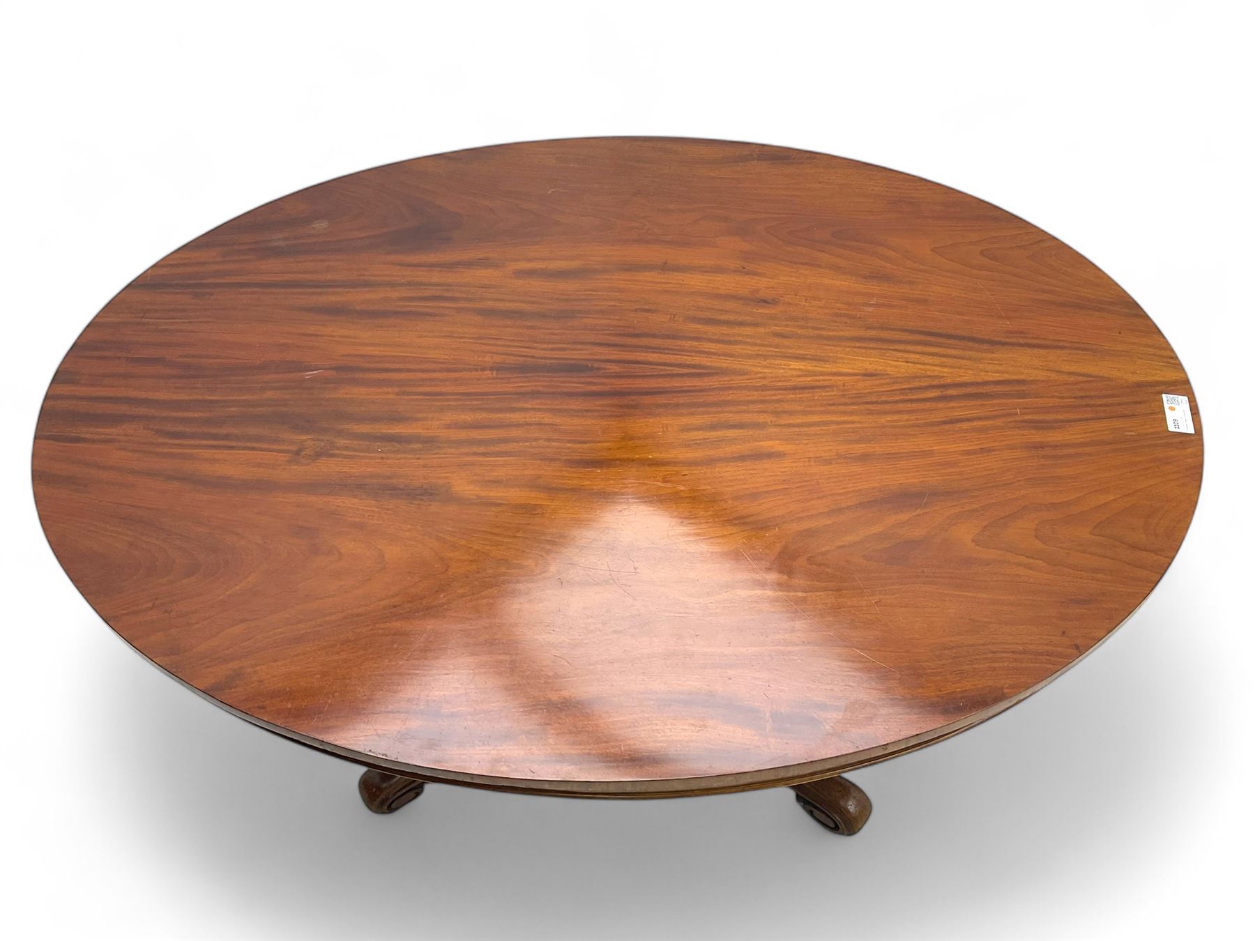 Victorian mahogany breakfast loo table, oval tilt-top on turned pedestal, quatrefoil out-splayed carved supports, scroll carved terminals with brass castors