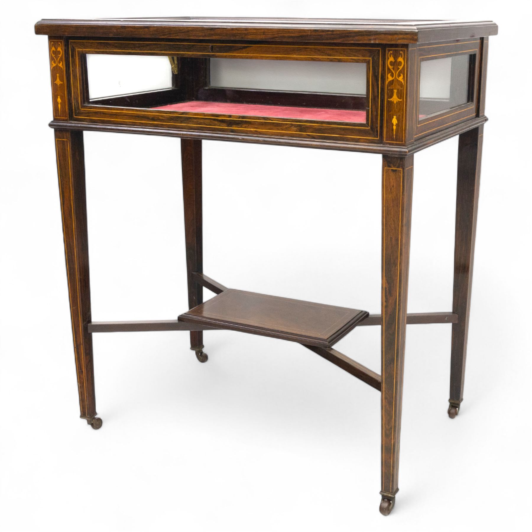 Edwardian rosewood bijouterie cabinet, the hinged rectangular top with line inlay enclosing a velvet lined interior, upon slender tapering legs inlaid with satinwood foliate marquetry decoration, with stretchers united by an under tier, raised on castors 