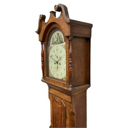 An Oak and Mahogany longcase clock with a Swans neck pediment and break arch hood door flanked by two ring turned pillars with capitals, trunk with a short door on a rectangular plinth with a shaped base, painted dial with Arabic numerals, quarter hour Arabic's, minute markers, subsidiary date and seconds dials and stamped brass hands, with matching painted spandrels and a depiction of a rural cottage and church to the arch, dial inscribed “Adinell, Selby”, with an eight-day rack striking movement, striking the hours on a cast bell. With weights and Pendulum


