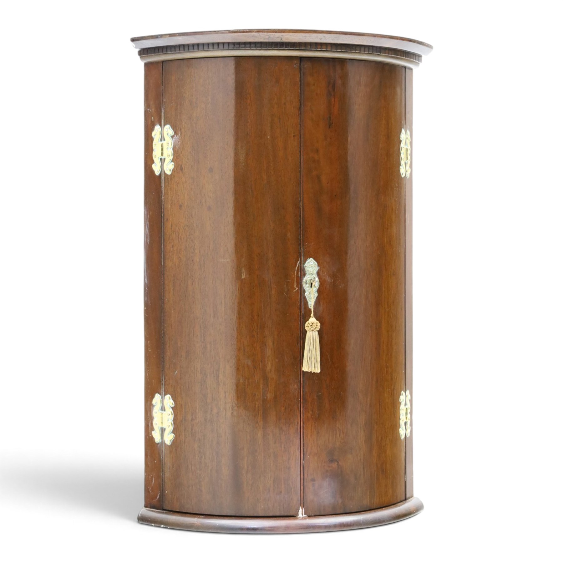 Small Georgian mahogany cylindrical hanging corner cabinet, projecting cornice with dentil carving, brass H hinges and escutcheons