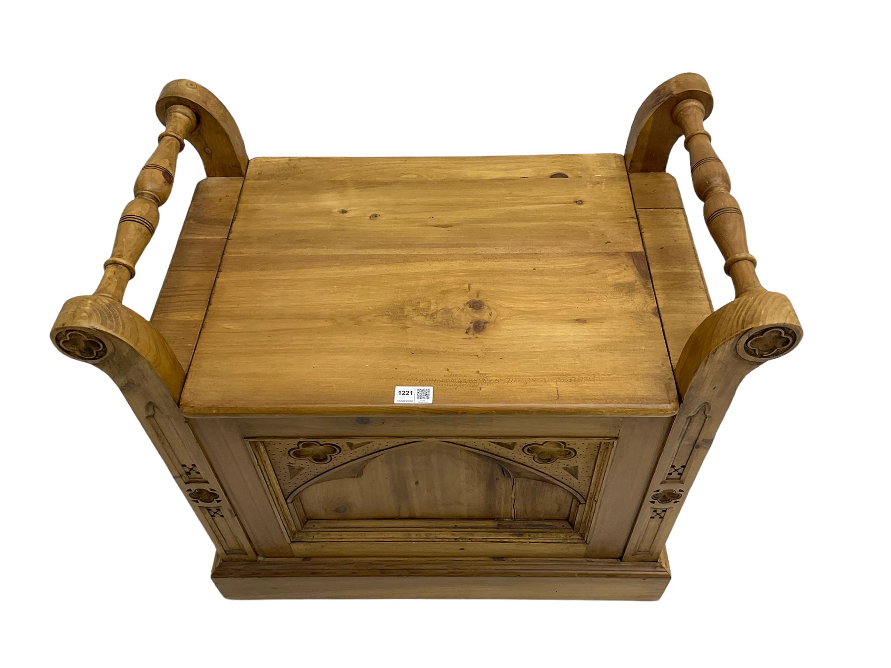 Gothic style pine stool with hinged box seat, decorated with flower head motifs, plinth base