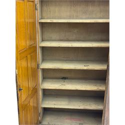 The North of England School Furnishing Company Limited Darlington - early 20th century oak school cupboard, projecting moulded cornice over two panelled doors, fitted with shelves, on chamfered plinth base 