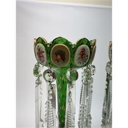 Pair of 19th century Bohemian green glass lustres, the castellated bowls decorated with overlaid panels of flowers and female portraits, upon tapering stems and overlaid spreading feet, heightened throughout with gilt, each supporting ten prismatic drops, H35cm