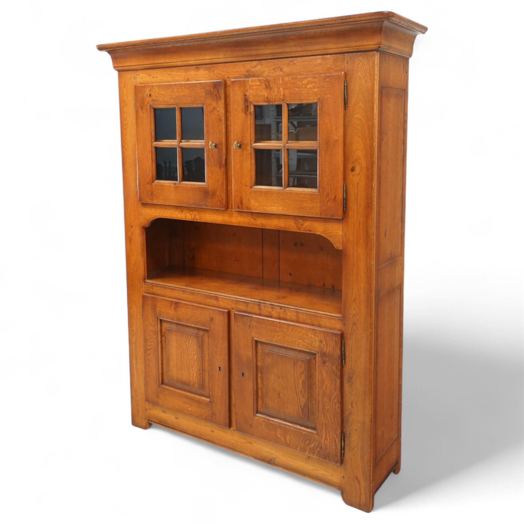 Traditional design solid oak dresser, moulded cornice over twin glazed doors enclosing shelved interior, open centre section, lower base with fielded panel doors opening to shelved cupboards, on plinth base
