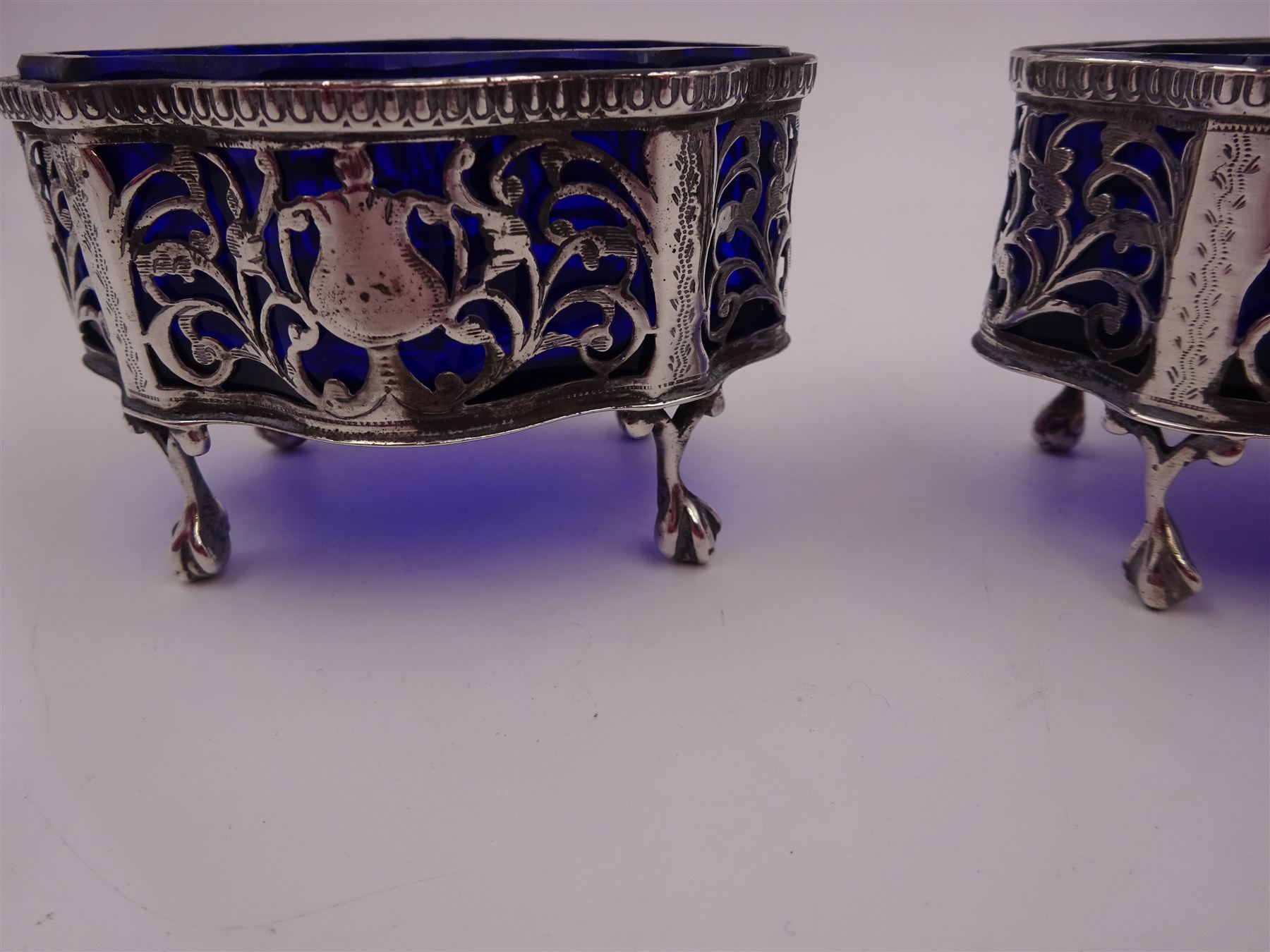 Pair of Victorian open silver salts with pierced sides, upon four ball and claw feet, hallmarked George Nathan & Ridley Hayes, Chester 1900, H5.2cm, each with blue glass liner