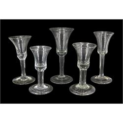 Five 18th century drinking glasses, the bell shaped bowls upon plain stems with internal tears or air bubbles and conical feet, four folded, tallest H17cm