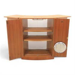 Turnidge of London - Mid 20th century teak drinks cabinet, shaped top with hinged fold-out side sections, twin doors with recessed handles enclosing fitted shelving and serving surfaces, sliding glass doors to the back, on a plinth base above castors