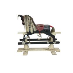 20th century black painted rocking horse on white painted trestle base, fitted with saddle and stirrups 