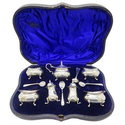 Edwardian silver seven piece cruet set, comprising four open salts of oval bellied form with shaped rim, upon four pad feet, mustard pot and cover, and pair of salts all of conforming design, hallmarked Birmingham 1908, makers mark J R Ltd, together with five matched Edwardian silver cruet spoons, contained within a fitted case with blue silk and velvet lined interior, approximate silver weight 9.67 ozt (301 grams)