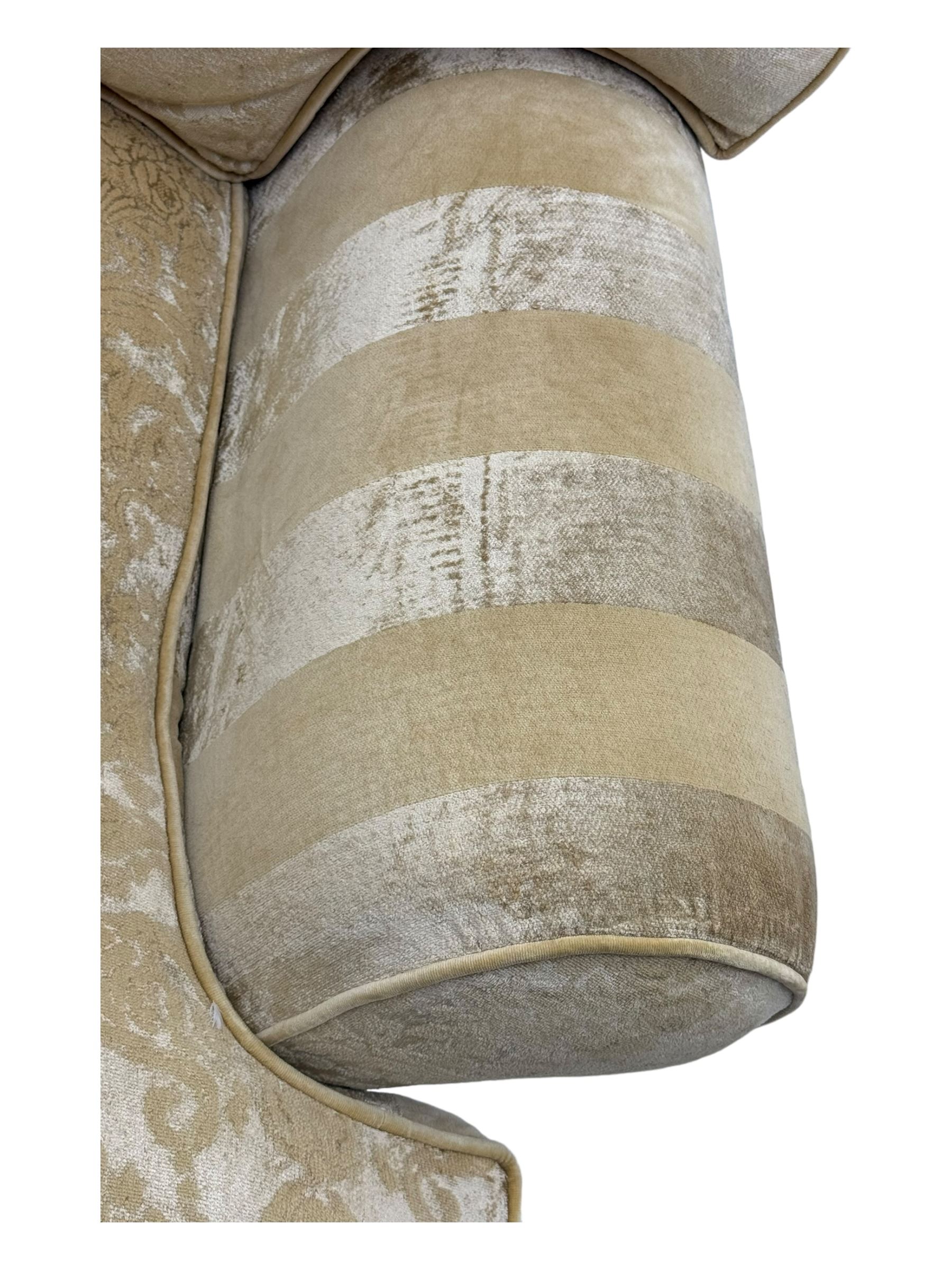 Contemporary two-seat sofa, upholstered in damask fabric with a pale gold floral pattern, rolled arms with covers, loose back and seat cushions, on matching skirted base with concealed castors