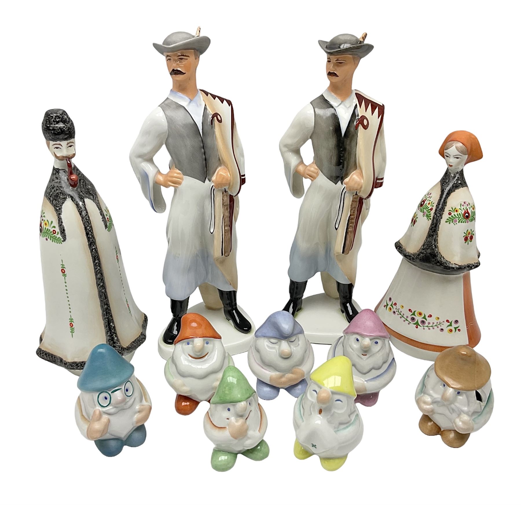 Group of eleven Aquincum of Budapest figures, comprising two of a man in a feather hat, seven dwarves, man and woman in traditional dress, all with printed marks beneath